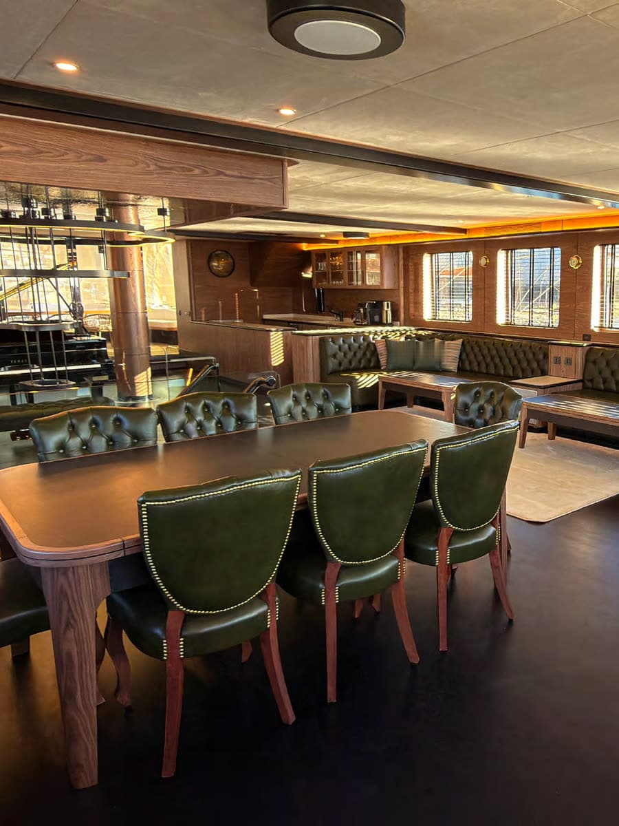 The saloon — green leather and American walnut, wide to the sea