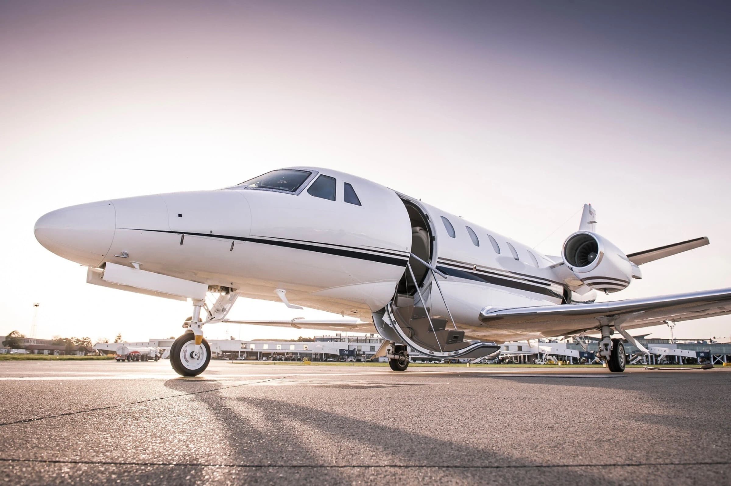 A private jet on the tarmac with its stairway lowered at sunset