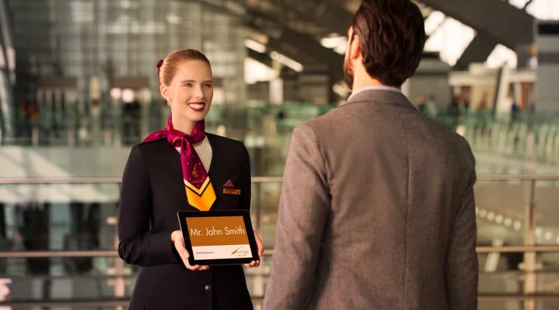 An airport hostess welcomes a traveller with a personalised name board
